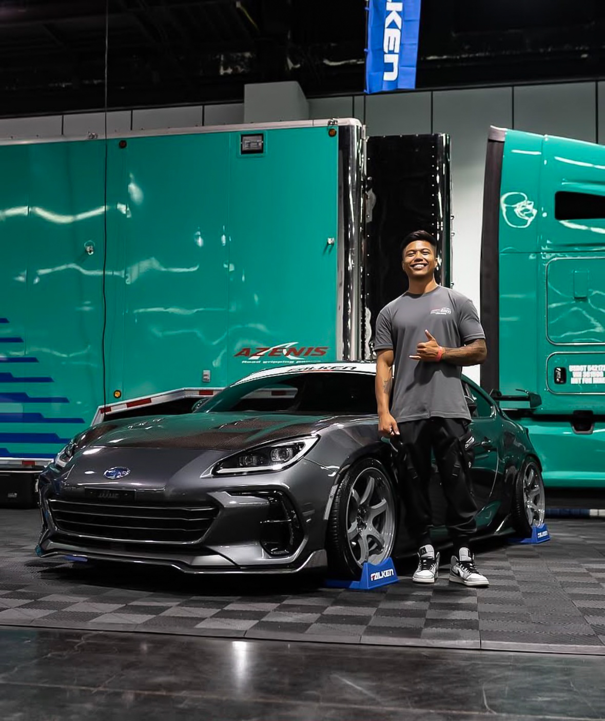 Gabriel standing beside a detailed sports car inside an automotive event space