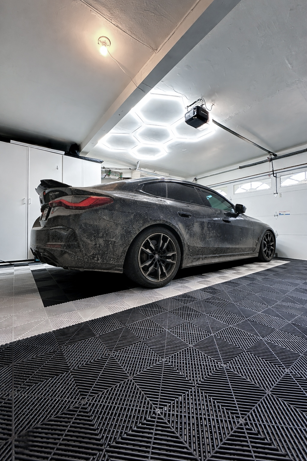 Black BMW before detailing, covered in road film inside the XP Garage workspace